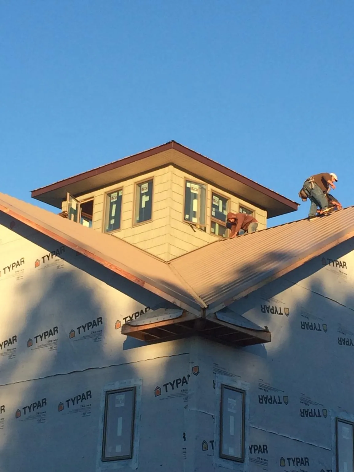 Roofers working around a rooftop cupola on a new metal roof at sunset — Roof Waterproofing in Worthing by Roofing Brothers